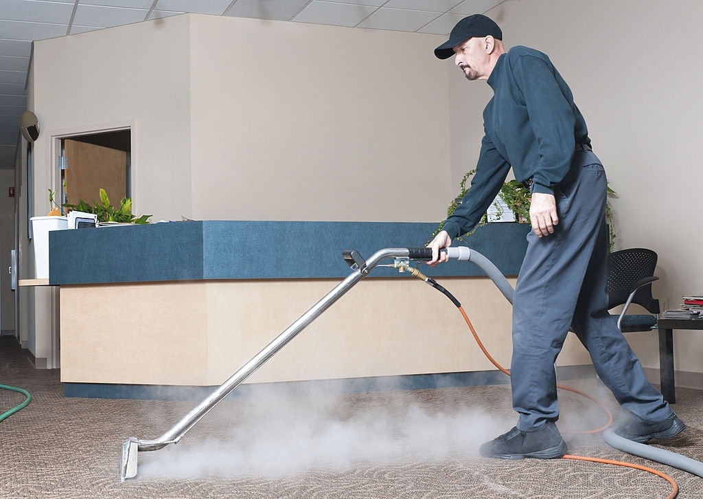 Man Steam Cleaning The Carpet Of An Office Building.